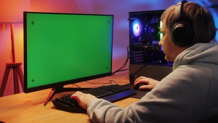 Computer with chroma key green screen on monitor. Gamer man playing in popular video games. Programmer or hacker coding a code and working in networks, cyberspace. Digital software, mobile app