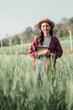 © Satori Studio - Cheerful female farmer stands with a digital tablet among tall wheat crops, embodying modern agricultural practices.