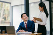 © Parichat - A man and a woman are sitting at a desk with a laptop and papers