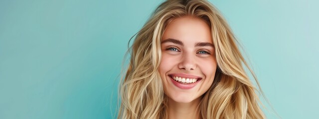 Wall Mural - A capturing the genuine smile of a young woman with blonde long groomed hair against a plain pastel background with copy space