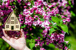 The girl holds in her hand the symbol of the house against the background of blooming weigela
