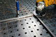 on a metal table for welding, the part lies clamped in a vice, the master is processing the part