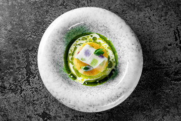 Wall Mural - visually stunning gourmet dish, meticulously layered in a speckled white bowl. The vibrant yellow base contrasts beautifully with the green elements on top.