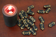 Burning black candle and many  runes on wooden table.