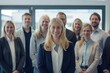 © yj - A group of smiling business people standing in an office, looking at the camera. In the center is a female manager with blonde hair. generative AI