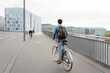 © Maskot - Businessman climbing cycle on sidewalk near railing in city