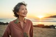 © CogniLens - Portrait of a tender asian woman in her 80s sporting a breathable hiking shirt isolated on beautiful beach sunset
