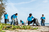 Fototapeta Sawanna - Group teamwork volunteer pick up the plastic bottle on the beach. People male and female Volunteer with garbage bags clean the trash on the beach make the sea beautiful. World environment day CSR.