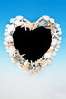 Seashell abstract heart shape frame with pearls and sea glass on blue white gradient background. Decorative nature design with exotic and tropical varieties.