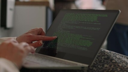 Closeup of unrecognizable female programmer checking program code typed on laptop black screen