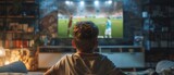Fototapeta  - An excited sports fan watches a soccer match on TV at home. The boy supports his favorite football team, feeling proud when players score a goal. Nostalgic and retro concept for childhood.