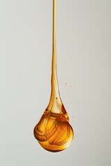 Wall Mural - Flowing subtle drop of golden thick liquid on a white isolated background.