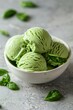 green basil ice cream in a white bowl on a light background with copy space, in a closeup view. 