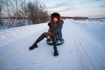 Wall Mural - a beautiful girl in a fur jacket and hat walks and has fun in the winter forest.