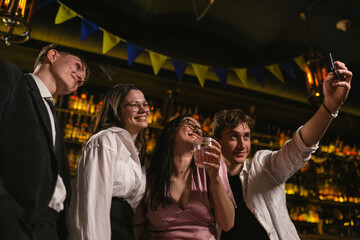 Nightlife after cocktail party in trendy restaurant. Young people drink alcoholic cocktails and relax at bar with patriotic flags