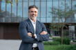 © Stock 4 You - Smiling confident latin hispanic mature business man standing crossed arms on busy city street. Proud portrait of older senior businessman professional ceo, coach, leader looking at camera near office