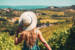Young female with summer hat and blue dress in Tuscany landscape in Italy