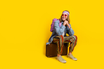 Wall Mural - Full size photo of cool young man sit valise look empty space wear denim shirt isolated on yellow color background