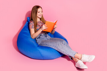 Full length photo of lovely teen lady sit bean bag read book dressed stylish print clothes isolated on pink color background