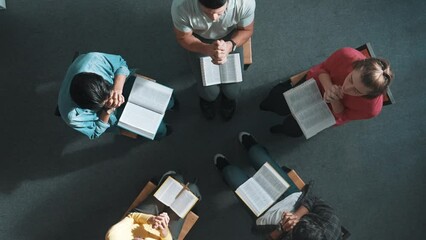 Wall Mural - Top down view of prayers reading bible with cross on the laps while making folded hands. Aerial view of diverse people praying to god with faith, trust and hope. and sitting in circle. Symposium.