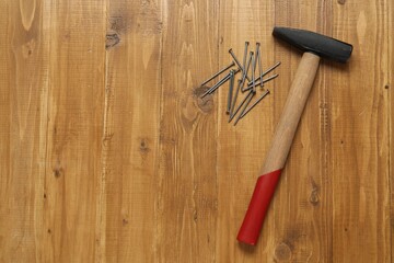 Poster - New hammer and metal nails on wooden table, flat lay. Space for text