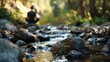 © Justlight - A stream flows through the forest providing a soothing soundtrack as the man meditates on the rocks.