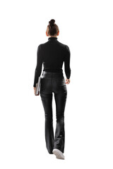 Wall Mural - A woman from behind holding a laptop, wearing black clothes and white sneakers, on a white background, concept of business attire