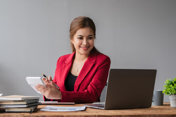 Wall Mural - Beautiful accountant sitting working with laptop calculating financial and tax figures for company on desk in living room.