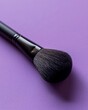 A single makeup brush positioned diagonally across a pastel lavender background, emphasizing its clean lines and minimalist beauty