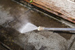 Concrete tile cleaning with pressure washer. Close up of high pressure water jet. Patio, balcony or deck spring cleaning. Dirty concrete tile. known as pressure or power washing. Selective focus.