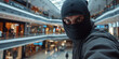 © IndigoElf - Unidentified anonymous man wearing a black balaclava covering his face at the shopping Center. Shoplifting, theft, security system.