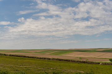 A large field with a blue sky and a few clouds. The sky is clear and the sun is shining