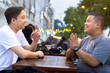 © Hardollin - Two Friends Cheerfully Chatting at Outdoor Cafe or Coffee shop