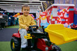 Little boy preschooler riding toy tractor at indoor playground