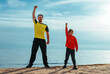 Father and son doing sports exercises on the beach at summer day