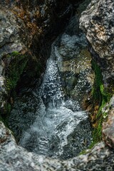 Poster - A scenic view of a stream flowing between two rocks. Perfect for nature and outdoor themes