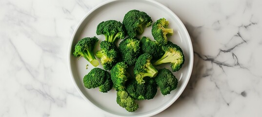 Poster - An image featuring steamed broccoli placed on a white plate against a plain background, isolated to draw focus, captured from above to showcase the arrangement, suitable for food photography.
