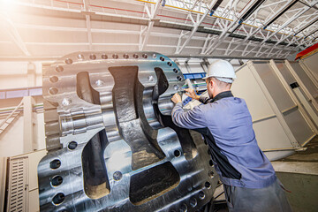 A working man is a man working at a factory on a metalworking machine in a worker's helmet