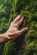 © Emanuel - Hand gently caressing moss growing on a massive tree trunk, embodying a deep connection with nature and a commitment to environmental stewardship, aligning with ESG principles