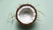 Half of a coconut with white flesh on a mint background, perfect for vegan and healthy recipes