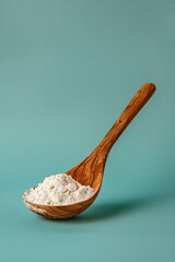 Wall Mural - white powder in wooden spoon, side view, photo, super quality, isolated, blue background, product photo