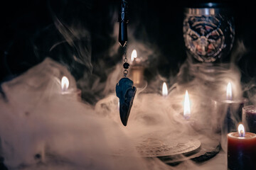 A mysterious and atmospheric occult setting featuring a pendulum swinging over a mystic symbol, surrounded by candlelight and fog.