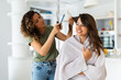 Hairstylist in a home visit, fully concentrated on work, cutting hair of a satisfied female costumer.