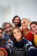 © CarlosBarquero - Vertical. Joyful Caucasian family smiling hugging taking a selfie photo indoor. Three generations Caucasian people looking at front camera at home. Happy people relations in domestic life