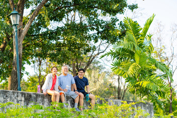 Wall Mural - Asian couple and elderly father resting after jogging exercise together at park. Retired man enjoy outdoor lifestyle sport workout in city. Family relationship and Senior people health care concept.