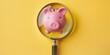 Piggy bank and magnifying glass on yellow background, savings and economy concept