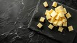 Elegant top view of butter pieces artfully arranged on a dark slate board, under sophisticated studio lighting, perfect for ads.