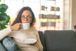 Latin woman drinking coffee on sofa at home