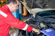 Senior Asian technician try to repair car engine with team for customer in car garage.