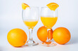 Two glasses of orange juice and oranges on a white background